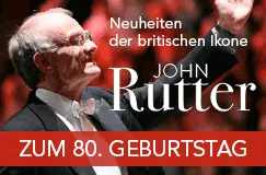 Text: "Zwei Neuheiten der britischen Ikone John Rutter. Zum 80. Geburtstag." Ein älterer Mann dirigiert, elegant gekleidet.