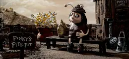 Eine traurige Figur sitzt auf einer Bank und hält eine Urne.
