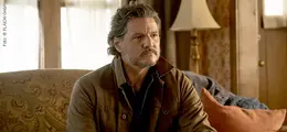 Ein nachdenklich wirkender Mann sitzt auf einem Sessel in einem gemütlichen Wohnzimmer mit Lampe und weichem Kissen.