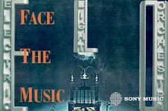 "Face the Music" in orange Schrift vor dunklem Hintergrund. Eindruck einer Bühne mit leuchtenden Elementen.