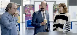 Drei Personen trinken Kaffee und unterhalten sich in einem modernen, offenen Raum.