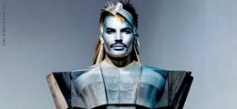 Ein an­d­ro­gyn wirkender Mensch in metallisch-futuristischer Rüstung, mit kantigen Formen und stacheliger Kopfverzierung.