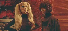 Foto von zwei Menschen im Vintage-Stil, umgeben von herbstlichen Farben; eine Person hat lange, blonde Haare.