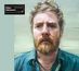 Text: "Glen Hansard RHYTHM AND REPOSE." Illustration eines Mannes mit rotem Bart und ernstem Blick in blauer Kleidung.