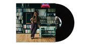 Eine Frau lehnt an einem Tisch, umgeben von Regalen voller Schallplatten und Büchern. Vinyl-Schallplatte rechts., LP