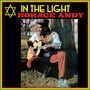 "IN THE LIGHT" und "HORACE ANDY". Ein Mann mit Gitarre sitzt vor einem Baum, trägt farbenfrohe Kleidung und einen Hut.
