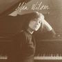 Oben steht handschriftlich „Mia Wilson“. Eine Frau lehnt sich lässig an ein Klavier., LP
