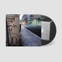 „Stone Age is Back“ steht auf einem Stromkasten. Daneben ist eine Zeichnung eines Tieres. Im Hintergrund eine leere Straße. CD mit Mauer-Motiv., CD
