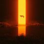 Eine schwebende Figur vor einem leuchtend orangefarbenen vertikalen Lichtstrahl, reflektiert in einem Gewässer., LP
