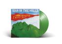 „MAN IN THE HILLS“ und „BURNING“ in lebhaften Farben über einer grünen Berglandschaft, grüne Vinyl-Schallplatte., LP