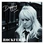 Text: "Duffy - Rockferry". Eine blonde Frau steht nachdenklich vor einem Zug. Schwarz-Weiß-Bild.