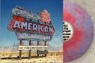 "The Good Ole American Saturday Night" steht auf einem nostalgischen Leuchtschild in einer Wüstenlandschaft. Links ist eine bunte Vinyl-Schallplatte., LP