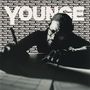 Text: "YOUNGE / ADRIAN YOUNGE" wiederholt im Hintergrund. Mann mit Brille schreibt konzentriert., LP