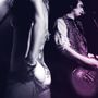Zwei Personen, verschwommen. Eine zeigt den Rücken mit einem Tattoo; die andere spielt Gitarre, verschwommen beleuchtet., 2 LPs