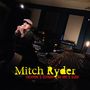 „Mitch Ryder“ in gelb, „Everyone’s servant, no one’s slave“ in rot. Ein Mann singt ins Mikrofon in einem Tonstudio.