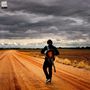 „JAKE BUGG ALAMO“ steht oben links. Eine Person mit Gitarre geht auf einer roten Straße unter einem bewölkten Himmel., CD