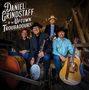 Text: „DANIEL GRINDSTAFF & THE UPTOWN TROUBADOURS“. Vier Männer mit Hüten und Instrumenten lachen, Hintergrund: Holzkonstruktion., CD