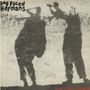 Oben links: "Dog Faced Hermans", unten rechts: "every day timebomb". Zwei Schattenfiguren mit Kameras auf einer Wand.