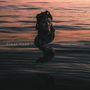 Texte: FINAL GASP, NEW DAY SYMPTOMS. Eine Statue steigt aus dunklem Wasser bei Sonnenuntergang., CD