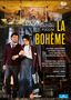 Text: Giacomo Puccini La Bohème. Namen der Künstler und Dirigenten. Zwei Personen in Bühnenkostümen, möglicher Theaterhintergrund.