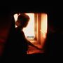 Text: "THERE'S A WHOLE WORLD OUT THERE." Silhouette einer Person am Fenster mit warmem, orangefarbenem Licht., LP