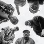 Es sind fünf Männer in einem Kreis, die in die Kamera blicken, teilweise mit Basecaps und Bandanas gekleidet., LP