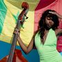 Eine Frau in einem grünen Kleid hält einen Kontrabass vor einer senegalesischen Flagge., Single 12"