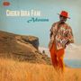 "Cheikh Ibra Fam" und "Adouna" in großen Buchstaben. Ein Mann in bunter Kleidung steht auf einer Wiese vor einer Küstenlandschaft., CD