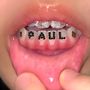 Text "PAUL" aus schwarzen Punkten auf den unteren Zähnen einer offenen Mundansicht mit glitzernden Details., 2 LPs
