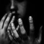 Die Nahaufnahme zeigt eine Hand mit schmutzigen Fingernägeln vor einem unscharfen, nachdenklich wirkenden Gesicht., LP