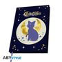 "Sailor Moon" in geschwungener Schrift über einer Illustration: eine lila Katze vor einem goldenen Mond und Sternen auf dunklem Hintergrund.
