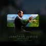 "JONATHAN JURION, GREEN WAGON, ARNAUD DOLMEN, DAMIAN NUEVA." Mann im Anzug sitzt seitlich, Hintergrund zeigt unscharfe Natur., CD
