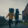 Zwei Menschen mit Tiermasken rennen auf einem Weg. Daneben eine schwarze Schallplatte., LP
