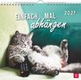 Text: „EINFACH MAL abhängen 2027“. Eine Katze liegt entspannt auf einem Sofa, hält eine Fernbedienung.