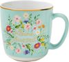 „Kleine Auszeit“ steht auf einer pastellblauen Tasse, umgeben von bunten Blumen., Diverse