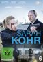 Cover von "SARAH KOHR", FSK 12. Zwei Personen am Hafen mit Waffen, eine blutende Frau im Vordergrund.