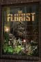 Text: "THE FLORIST". Ein Schaufenster zeigt Blumen und subtil ein Gewehr im Hintergrund., DVD