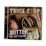"Vorab Cover", "Truck Stop", "Butter bei die Fische". Eine Dose Sardinen auf Holztisch neben Brot.