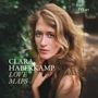 "CLARA HABERKAMP LOVE MAPS" in Großbuchstaben. Eine Frau mit langen, lockigen Haaren schaut direkt in die Kamera, umgeben von grüner Natur., CD