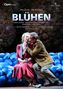 "BLÜHEN" wird groß gezeigt. Paar sitzt auf blauen Kissen, Mann küsst Frau liebevoll. Oper Frankfurt Logo oben links., DVD