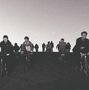 Keine Texte sichtbar. Mehrere Menschen fahren mit Fahrrädern auf einem Hügel und sind gegen den Himmel silhouettiert., CD