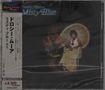 Text links: "ドルシー・ムーア ミスティ・ブルー +1" und Preisangabe. Bild: Frau sitzt auf einem Rattanstuhl vor einem dunklen Hintergrund.