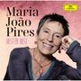 Text: "Maria João Pires Best of Best". Porträt einer lächelnden Frau mit kurzem Haar vor rosa Hintergrund. Oben rechts kleines gelbes Logo.