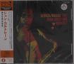 Text: "AFRICA/BRASS THE JOHN COLTRANE QUARTET". Japanische Schriftzeichen links. Jazzmusiker mit Saxophon, dunkler Hintergrund.