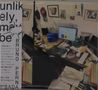 Text: "unlikely, maybe BRUNO PERNA". Ein chaotischer Schreibtisch mit Computer, Notizen, Fotos an der Wand., CD