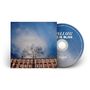 "LOVE IS BLISS" in Großbuchstaben auf einer CD. Ein Baum vor einem Gebäude und blauer Himmel im Hintergrund., CD
