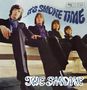 „…It's Smoke Time“ in blauer, geschwungener Schrift oben. „The Smoke“ in Weiß unten. Vier Männer in Anzügen sitzen auf einer Bank.