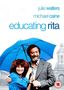 „Julie Walters, Michael Caine, Educating Rita“ – Fröhliche Frau mit lockigem Haar unter blauem Regenschirm, Mann daneben.