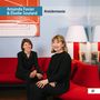 „Amanda Favier & Élodie Soulard – Kreislermania“. Zwei Frauen sitzen lächelnd auf einem roten Sofa in einem modernen Raum., CD
