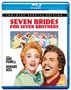 "SEVEN BRIDES FOR SEVEN BROTHERS" in roter Schrift. Darunter ein glückliches Paar und eine Gruppe von Menschen.